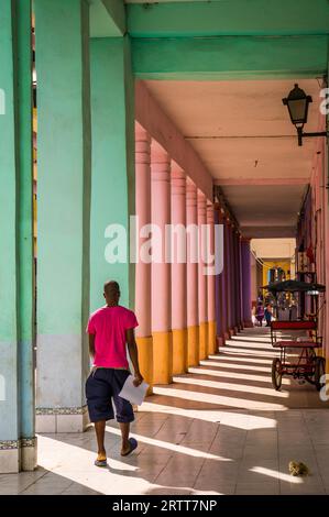 La Havane, Cuba le 23 décembre 2015 : un homme cubain en chemise rose décontractée marchant à travers un passage coloré transportant des documents Banque D'Images