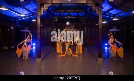 un groupe de danseurs sundanais avec du jasmin et des châles jaunes dansent sur scène la nuit Banque D'Images