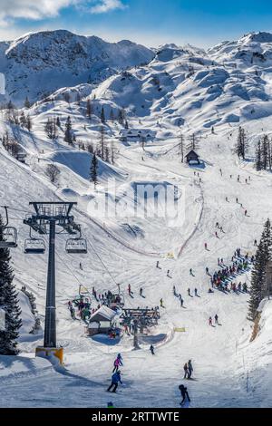 Bohinj, Slovénie - vue hivernale de la montagne enneigée de Vogel avec des skieurs sur les pistes de ski et remontées mécaniques dans les Alpes au parc national du Triglav sur une winte ensoleillée Banque D'Images