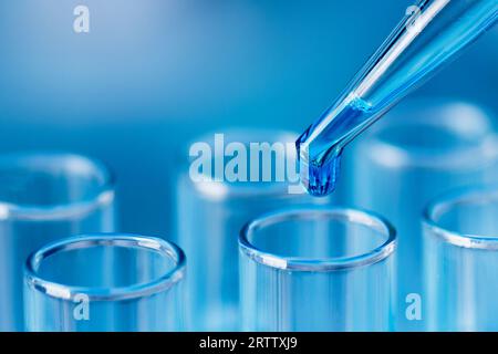 Tubes à essai avec échantillons d'eau liquide bleus et pipette sur fond bleu. Pipeter l'échantillon en le déposant dans le tube à essai. Verrerie de laboratoire, labo scientifique Banque D'Images