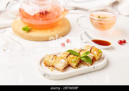 Théière en verre de thé aux baies sain naturel et baklava turc traditionnel avec miel et menthe- réglage de table esthétique. Espace de copie. Banque D'Images