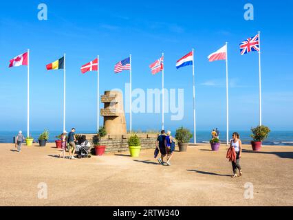 Les touristes se promènent autour du monument signal à Bernières-sur-Mer, en France, érigé en 1950 sur le site du débarquement de Normandie de Juno Beach. Banque D'Images
