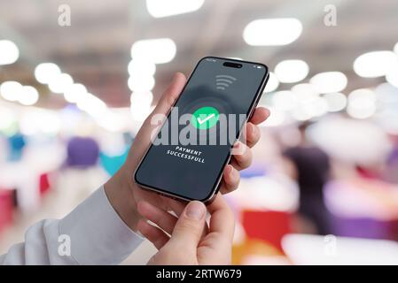 Téléphone mobile en mains avec notification de paiement réussie sur l'affichage dans un magasin, présentant des transactions modernes pour un shopping délicieux ex Banque D'Images