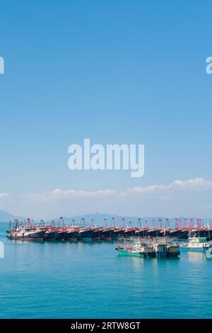 Un ensemble de bateaux amarrés les uns près des autres dans la mer avec les bateaux plus petits situés sur le rivage Banque D'Images