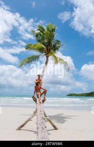 Couple multiracial diversifié en vacances à Oh Kood Island Thailand Trat, un couple d'hommes et de femmes assis à un palmier suspendu sur une journée ensoleillée pendant les vacances Banque D'Images