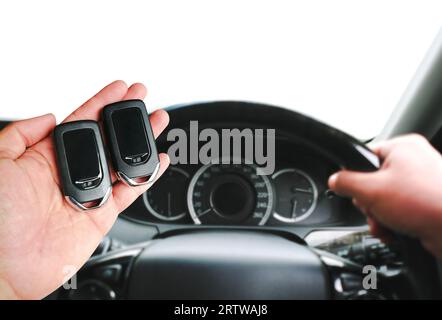 Main du conducteur tenant une télécommande d'entrée sans clé pour démarrer ou arrêter le moteur. Deux télécommandes de voiture sans clé dans la main du conducteur pour comparaison. Copier l'espace, Concep Banque D'Images