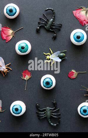 motif halloween avec globes oculaires, insectes et roses rouges sur fond noir Banque D'Images