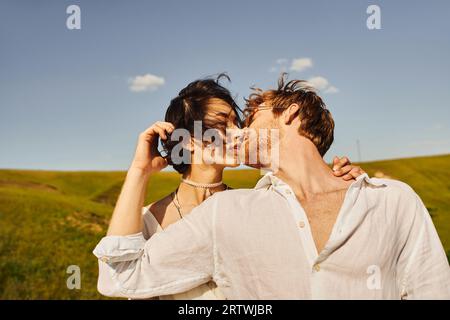 juste marié couple interracial embrassant sur le vent sous le ciel bleu, mariage rustique dans un cadre tranquille Banque D'Images