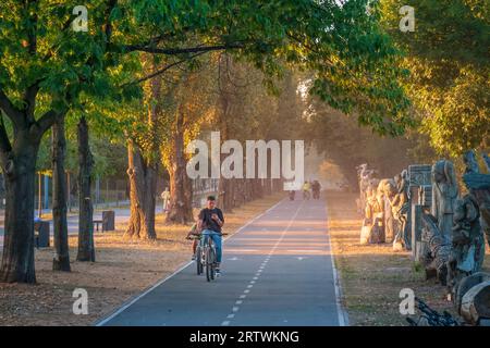 2023-09-10 Kiev, Ukraine. Piste cyclable dans le parc de la ville avec des gens à vélo. Chaude soirée d'automne dans le parc Banque D'Images