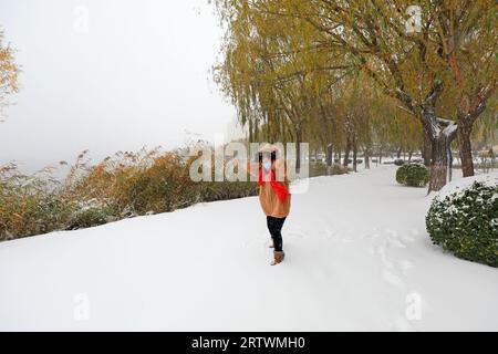 COMTÉ de LUANNAN, Chine - 7 novembre 2021 : une femme marche dans une tempête de neige avec un parapluie dans un parc, dans le nord de la Chine Banque D'Images