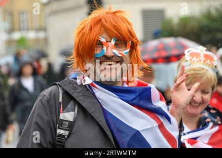 Une femme descend Piccadilly sous la pluie, faisant partie de la foule nombreuse qui se dirige vers le couronnement du roi Charles III. Piccadilly, Londres, Royaume-Uni. 6 mai 2023 Banque D'Images