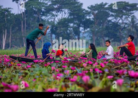 Les voyageurs se déplacent sur un petit bateau à l'intérieur d'un grand plan d'eau appelé `Shatla beel' rempli de nénuphars rouges, à Ujirpur dans Barisal. Bangladesh. Banque D'Images