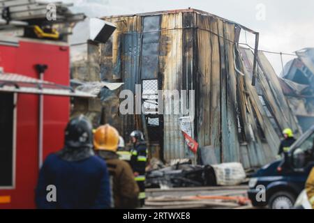 Grand incendie de flamme massive dans la ville, usine d'entrepôt flamboyante, bâtiment de stockage brûle, équipe de pompiers éteignant le feu, pompiers en service, Banque D'Images