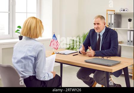 Femme assise au bureau des services publics ou de l'ambassade des États-Unis et ayant un entretien de visa. Banque D'Images