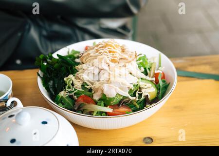 Assiette blanche avec salade et mayonnaise sur une table en bois, prête à manger Banque D'Images