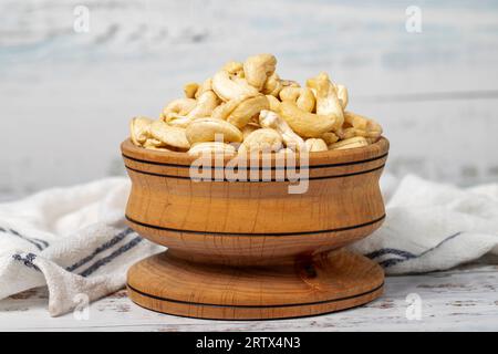 Noix de cajou dans un bol en bois. Noix de cajou rôties sur fond de bois blanc Banque D'Images