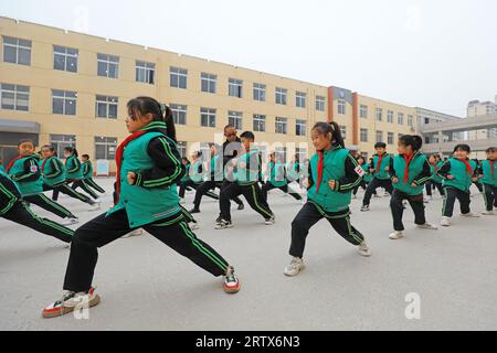 COMTÉ de LUANNAN, Chine - 9 décembre 2021 : les élèves du primaire pratiquent les compétences de base des arts martiaux traditionnels chinois sur le campus Banque D'Images