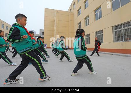 COMTÉ de LUANNAN, Chine - 9 décembre 2021 : les élèves du primaire pratiquent les compétences de base des arts martiaux traditionnels chinois sur le campus Banque D'Images