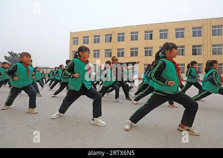 COMTÉ de LUANNAN, Chine - 9 décembre 2021 : les élèves du primaire pratiquent les compétences de base des arts martiaux traditionnels chinois sur le campus Banque D'Images