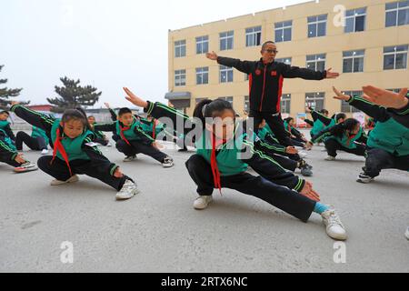 COMTÉ de LUANNAN, Chine - 9 décembre 2021 : les élèves du primaire pratiquent les compétences de base des arts martiaux traditionnels chinois sur le campus Banque D'Images