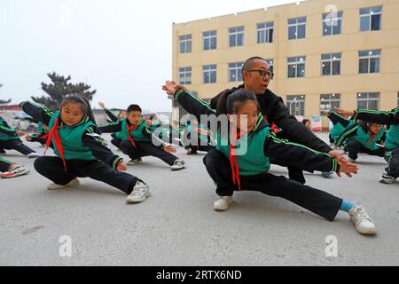 COMTÉ de LUANNAN, Chine - 9 décembre 2021 : les élèves du primaire pratiquent les compétences de base des arts martiaux traditionnels chinois sur le campus Banque D'Images