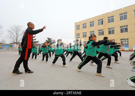 COMTÉ de LUANNAN, Chine - 9 décembre 2021 : les élèves du primaire pratiquent les compétences de base des arts martiaux traditionnels chinois sur le campus Banque D'Images