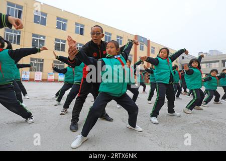 COMTÉ de LUANNAN, Chine - 9 décembre 2021 : les élèves du primaire pratiquent les compétences de base des arts martiaux traditionnels chinois sur le campus Banque D'Images