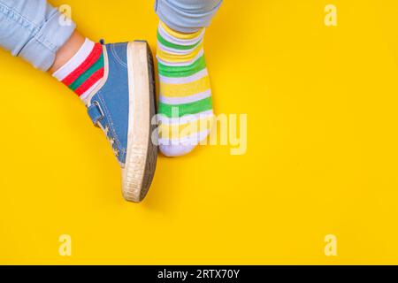 ODD Socks Day, Lonely Sock Day. Semaine anti-intimidation, sensibilisation au syndrome de Down. Jambes d'enfant portant une paire différente de chaussettes dépareillées sur ba haute couleur Banque D'Images