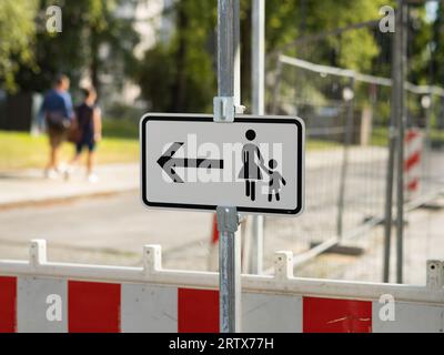 Panneau de signalisation allemand pour les piétons de changer de côté de la rue en raison d'un chantier de construction. Détour pour les gens sur le trottoir. Banque D'Images