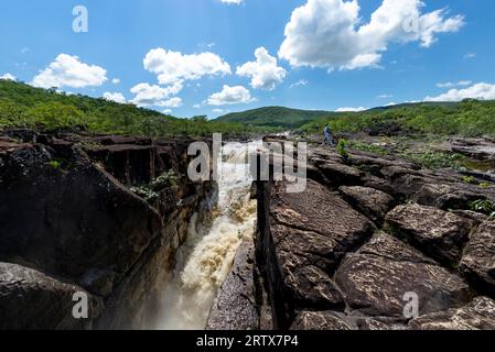 femme touriste debout sur le bord d'une falaise et regardant la cascade. chapada dos veadeiros, Brésil Banque D'Images