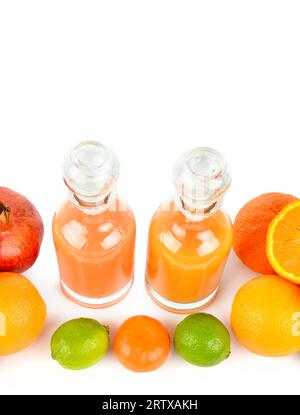 Jus d'agrumes dans des carafes en verre et un ensemble de fruits isolés sur un fond blanc. Photo verticale. Espace libre pour le texte. Banque D'Images