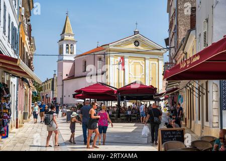 Cafés en plein air animés sur la place de la liberté (Trg Slobode), avec l'église notre-Dame des Anges en arrière-plan, à Poreč sur la péninsule d'Istrie en Croatie Banque D'Images