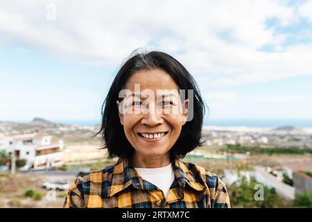 Heureuse femme thaïlandaise s'amusant s'amusant souriant dans la caméra sur le toit de la maison Banque D'Images