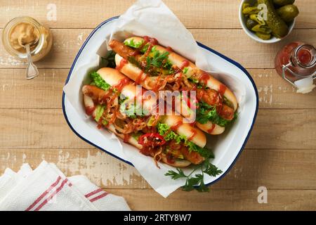 Délicieux hot-dog grillé avec concombres marinés, piments, oignons caramélisés et ketchup, moutarde en papier artisanal sur vieux fond de bois. Homem Banque D'Images