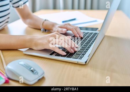 Gros plan des mains d'une jeune étudiante tapant sur un ordinateur portable Banque D'Images