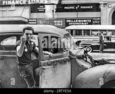 San Francisco, Californie : c. 1955 Un adolescent grimpant dans le beatup hot Rod de son ami qui a le capot manquant. Banque D'Images