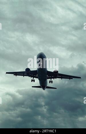 Vue rapprochée de gros avions atterrissant dans les nuages massifs sombres. Avions et thème de l'aviation Banque D'Images