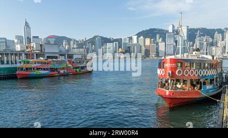 Deux vieux Star Ferries amarrés dans le port de Kowloon surplombant les gratte-ciel de Hong Kong par une journée ensoleillée. Hong Kong - 30 août 2023 Banque D'Images