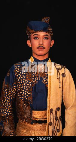 Un homme asiatique portant un costume de danse traditionnelle indonésienne est brun et son visage est plein de maquillage dans une chambre Banque D'Images