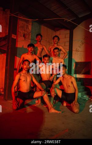 un groupe d'hommes sans vêtements dansant pose dans un vieux bâtiment avec une lumière rouge la nuit Banque D'Images