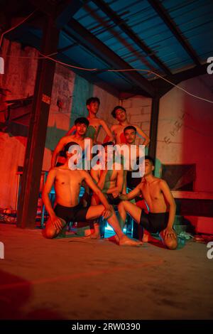 un groupe d'hommes sans vêtements dansant pose dans un vieux bâtiment avec une lumière rouge la nuit Banque D'Images