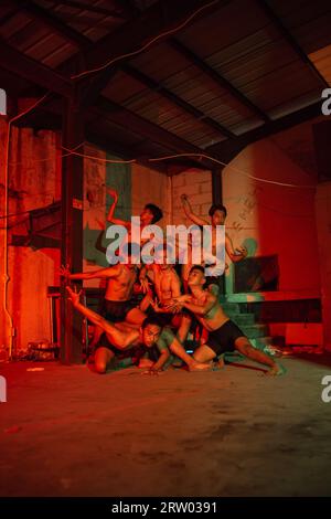 un groupe d'hommes sans vêtements dansant pose dans un vieux bâtiment avec une lumière rouge la nuit Banque D'Images