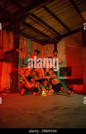 un groupe d'hommes sans vêtements dansant pose dans un vieux bâtiment avec une lumière rouge la nuit Banque D'Images