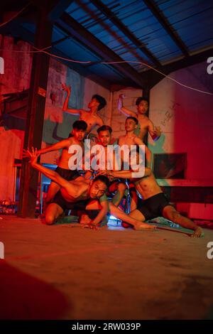 un groupe d'hommes sans vêtements dansant pose dans un vieux bâtiment avec une lumière rouge la nuit Banque D'Images