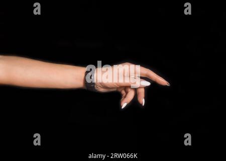 La main d'une femme tendue appuie les mains de la fille avec ses doigts contre le fond noir. Banque D'Images