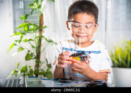 Petit enfant essayant d'assembler la roue de construction au jouet de voiture Banque D'Images