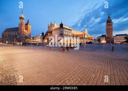 Vieille ville de Cracovie au crépuscule en Pologne, place du marché principal, sur la gauche St. Église de Marie (Église Mariacki) (Bazylika Mariacka) salle aux draps (Sukiennice) Banque D'Images