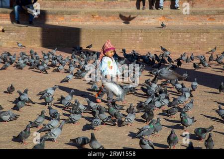 Katmandou, Népal, 19 octobre 2014 : un garçon entouré de pigeons sur la place historique Durbar Banque D'Images