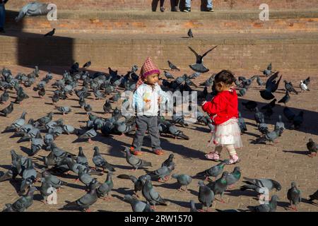 Katmandou, Népal, 19 octobre 2014 : deux enfants entourés de pigeons sur la place historique Durbar Banque D'Images