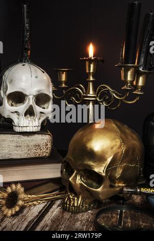 Une image de bougies dans un chandelier, un crâne avec des gouttes de cère, un autre or et une bougie allumée Banque D'Images